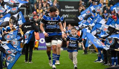 Ewan Richards of Bath Rugby runs out at The Rec with a young supporter through the guard of honour.