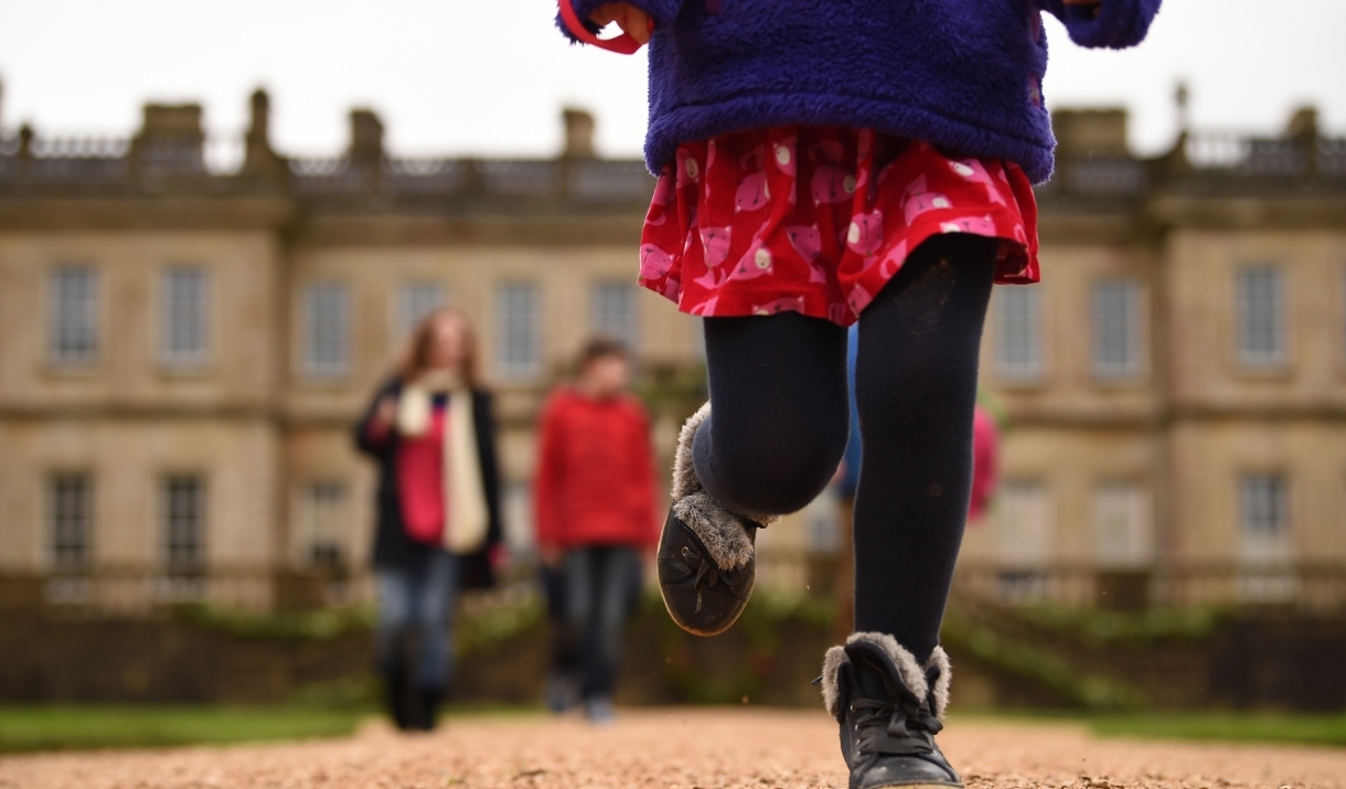 A child running on the path outside Dyrham Park house