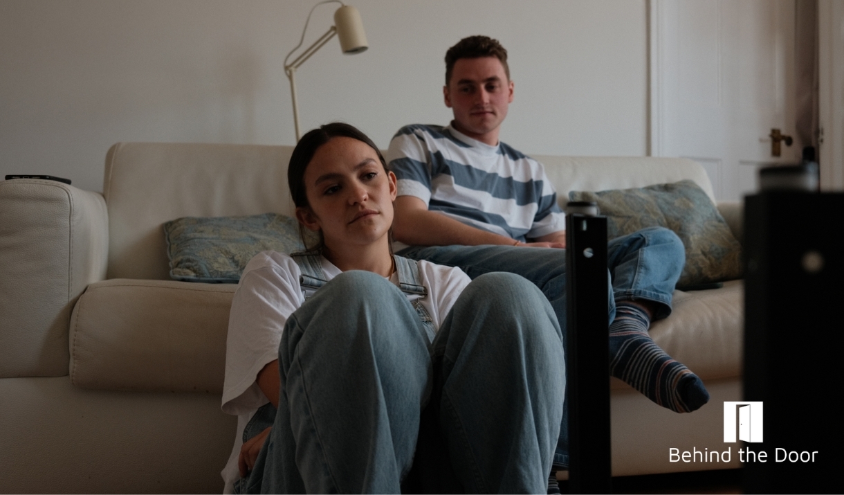 Two people. The male is sitting on a sofa and the female in front of him on the floor.