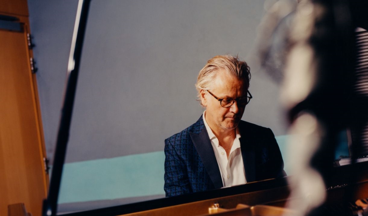 Guy Chambers sat at a piano