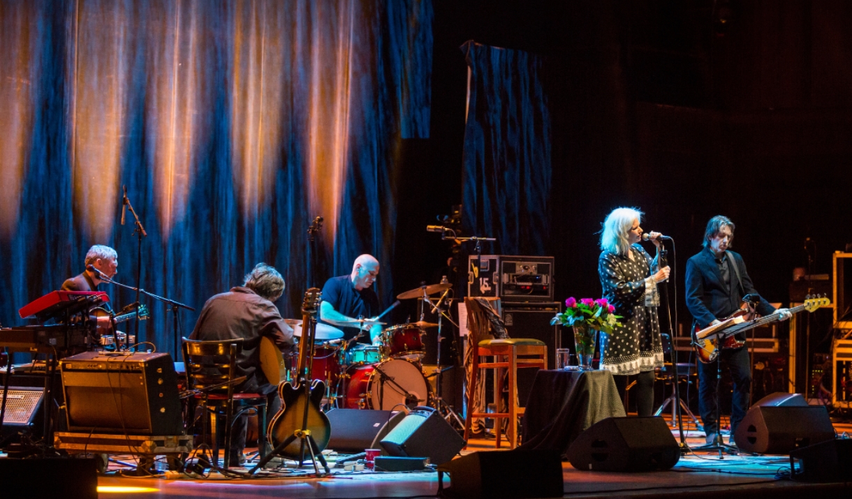 Live band performing on stage under blue and amber lighting.