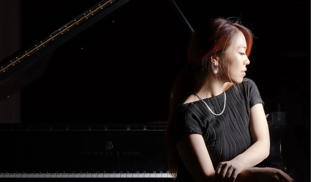 Female musician posing next to piano