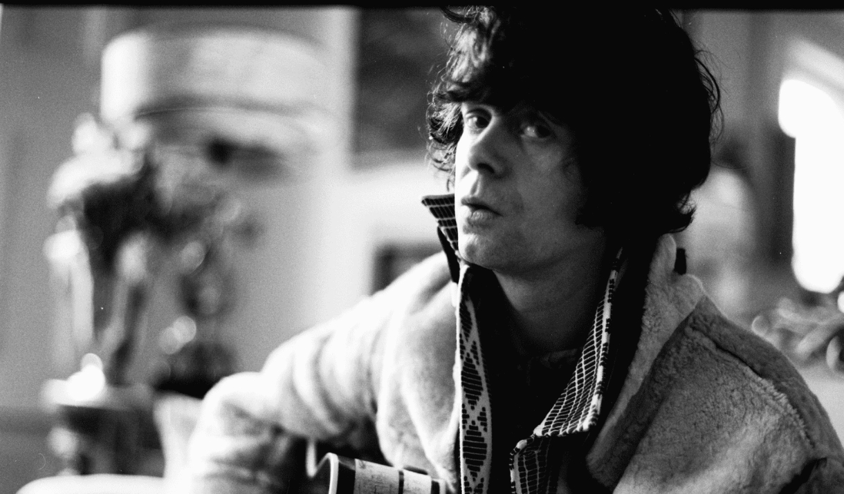 Black and white portrait of a musician holding a guitar indoors.