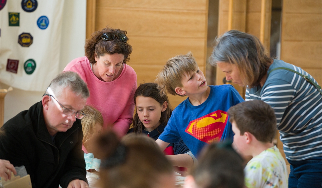 Photo of families around a table in a bright room, crafting together