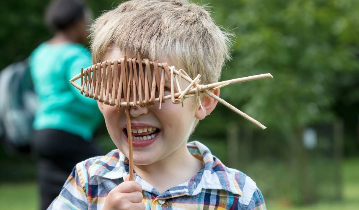 boy outside peeping through fish made from small sticks