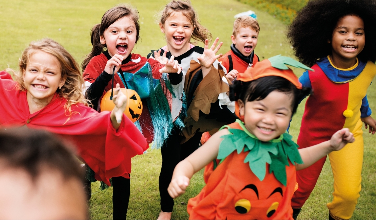 Group of children in Halloween costumes running outside