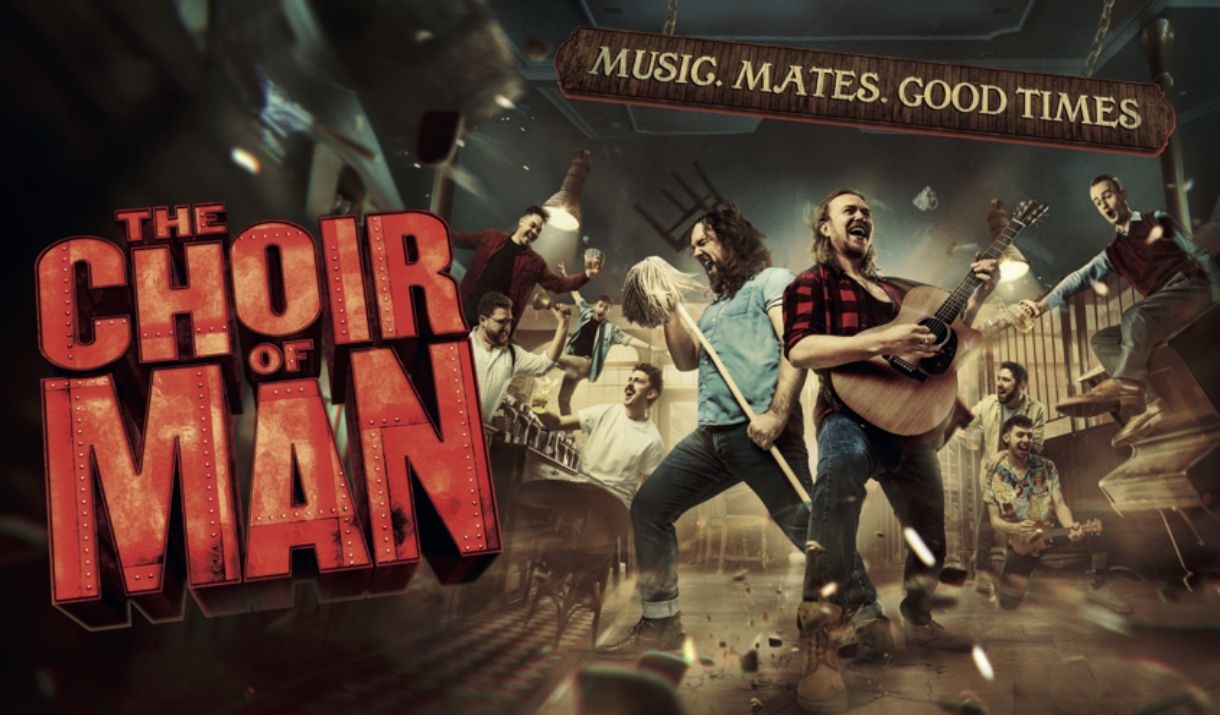 A group of male friends are singing and dancing around a bar with the words 'THE CHOIR OF MAN' displayed.