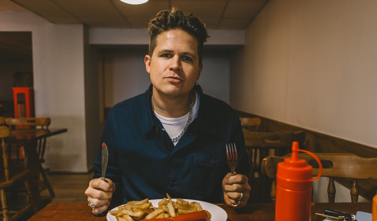 Luke Wright sat at a table with sausage and chips