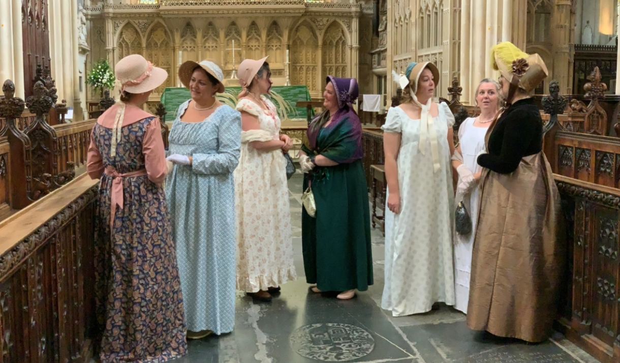 Women dressed in Jane Austen themed regency wear stood inside Bath Abbey