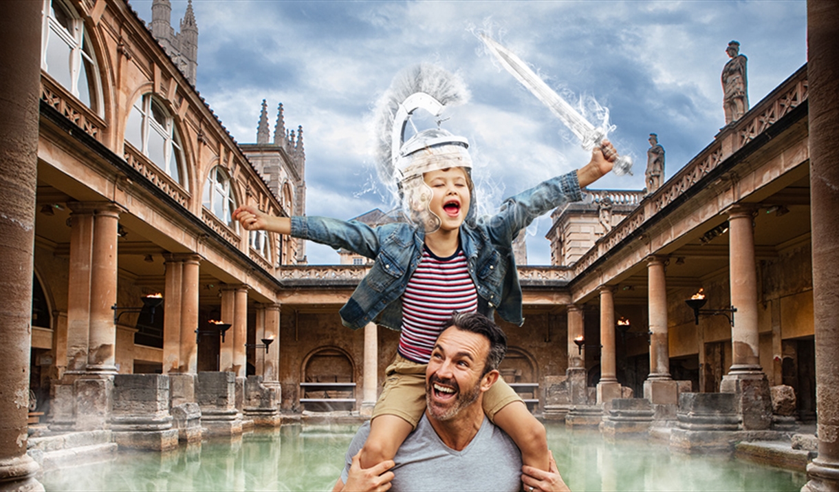 Father and son at the Roman Baths. Boy sits on fathers shoulders as the steam from the water of the Baths creates a Roman shield on his head and sword