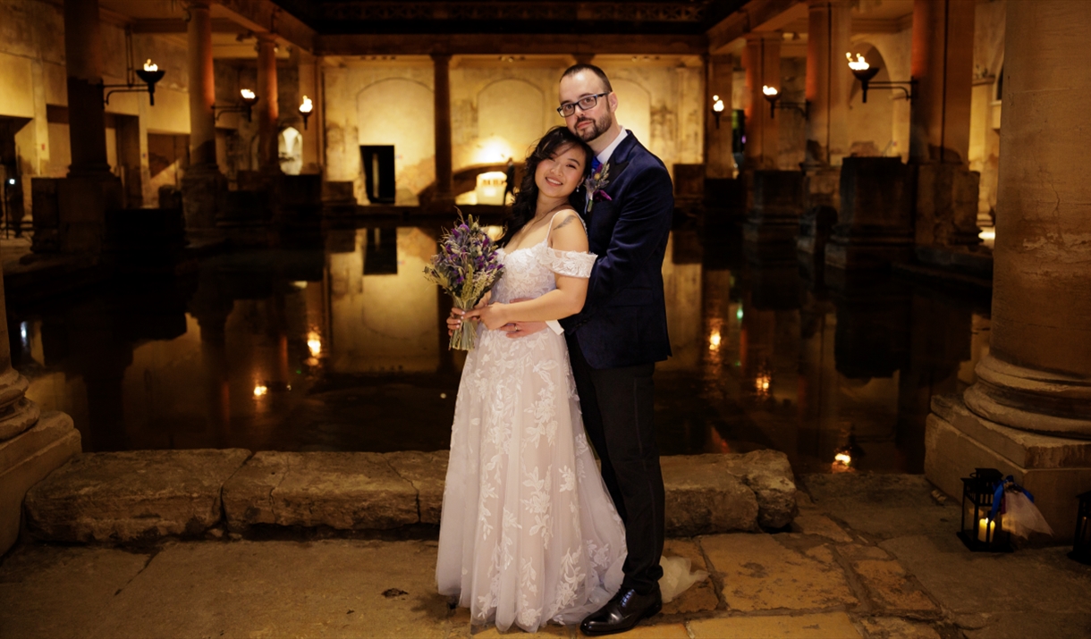 A bride and groom alongside The Great Bath at The Roman Baths