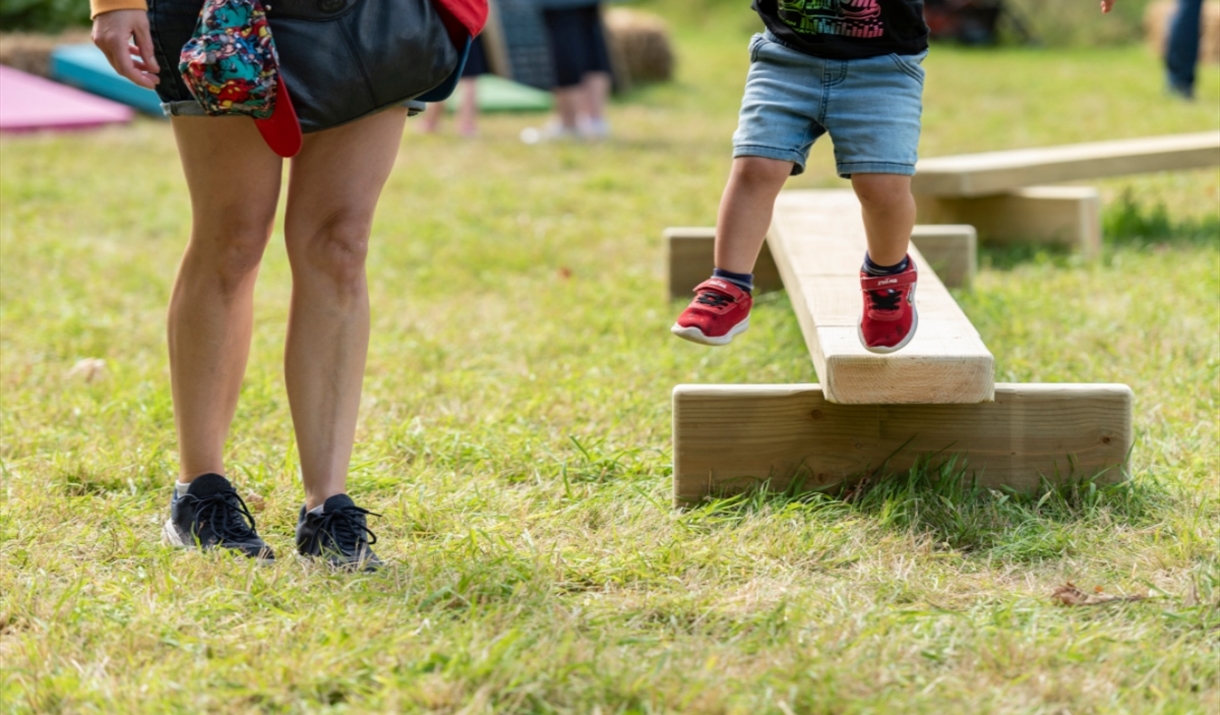 A family playing on balance beams at a National Trust Summer of Play event. Image credit: National Trust Images/Paul Harris