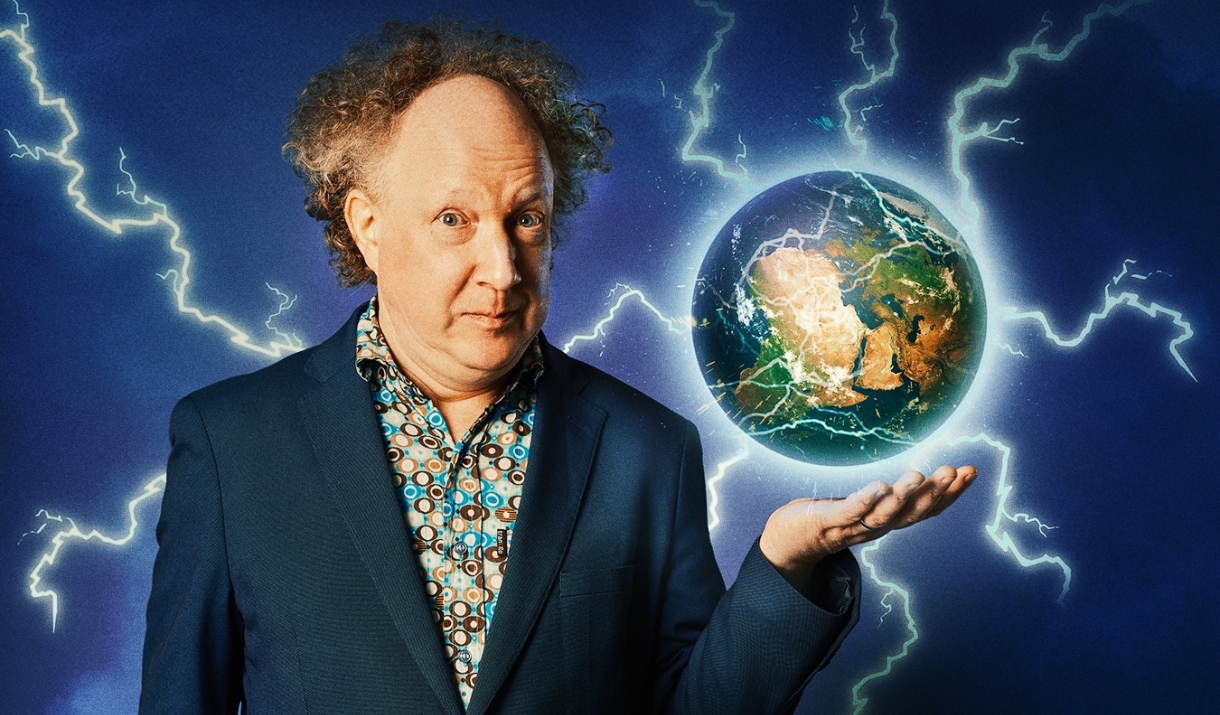 A photo of Andy Zaltzman, his holing a globe of the earth. Lighting is is shooting from the globe.