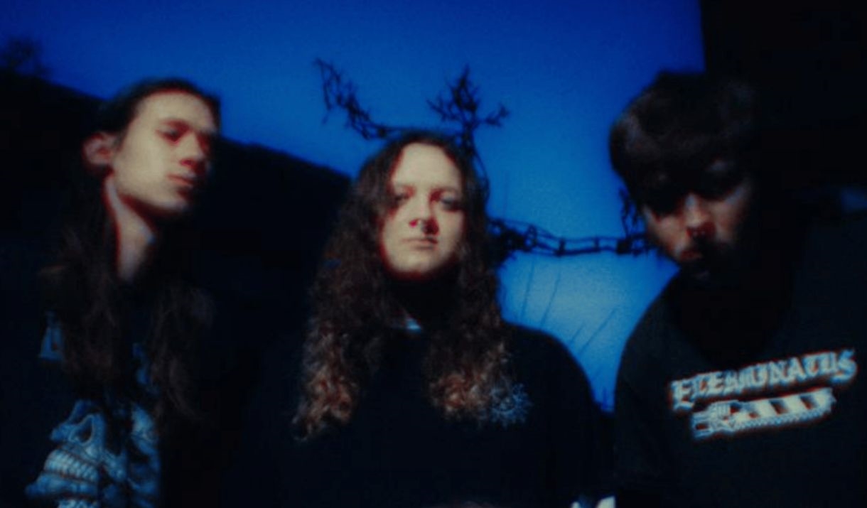 A somewhat blurry image of 4 alternative band members dressed in predominantly all black. The Sparkfest logo in the corner