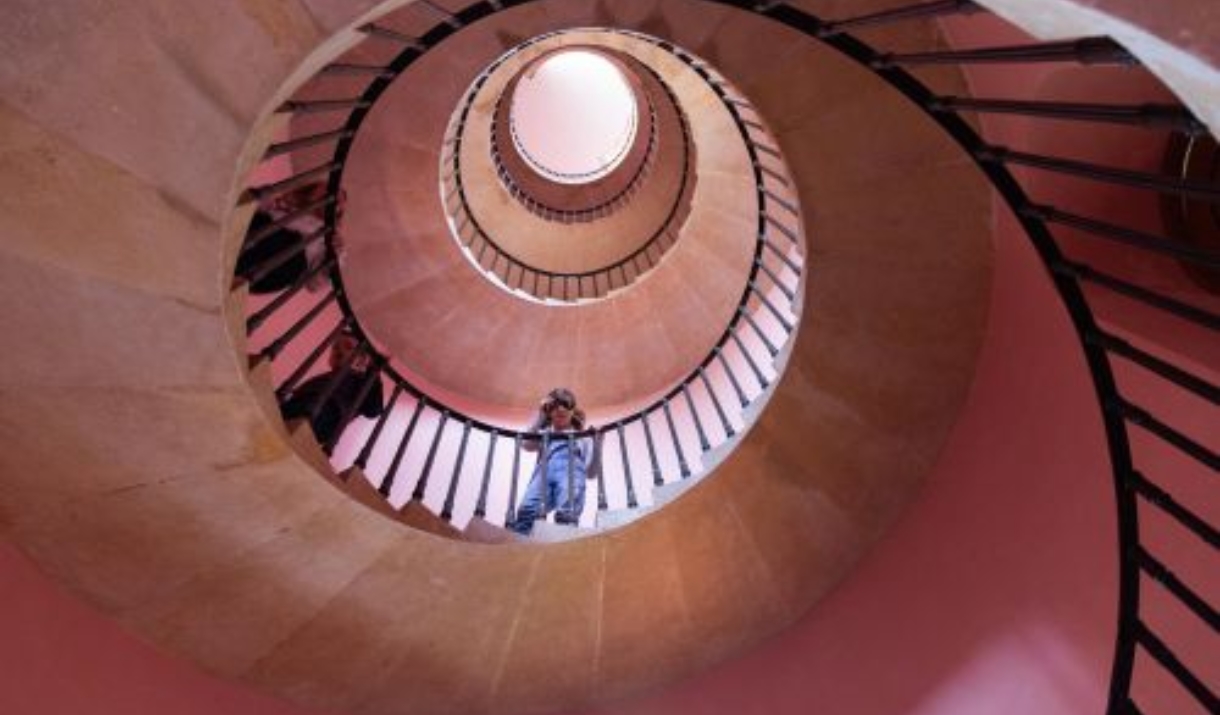 Photo of girl looking down at the camera from a spiral staircase