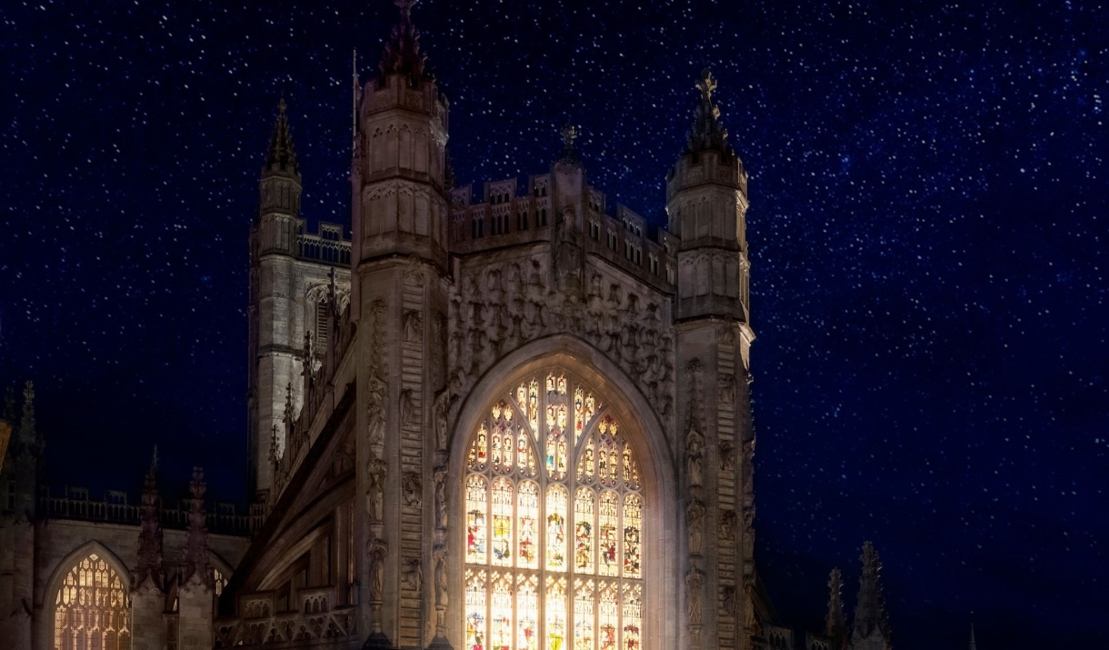 Bath Abbey lit up from inside with stars behind