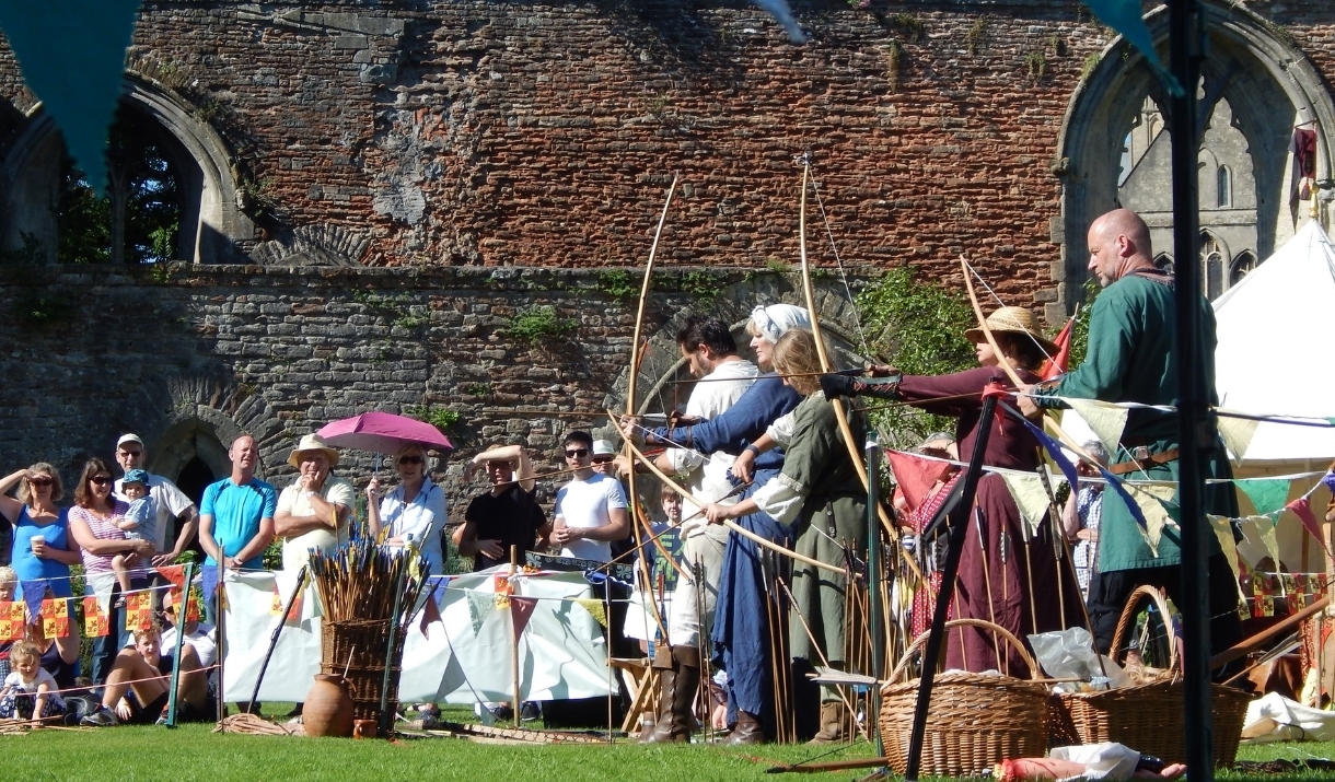 People in medieval dress firing arrows with a crowd watching.