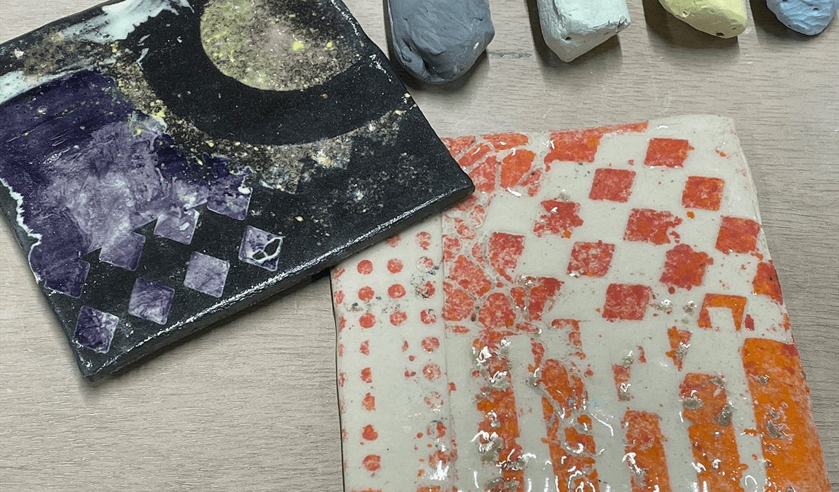 Two ceramic tiles with three sticks of chalk above