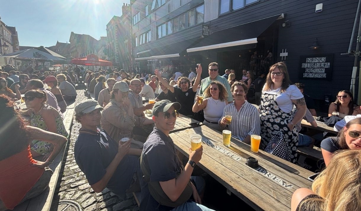 people sitting outside in the sun with a drink in hand