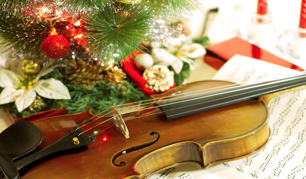 A violin surrounded by Christmas lights and ornaments