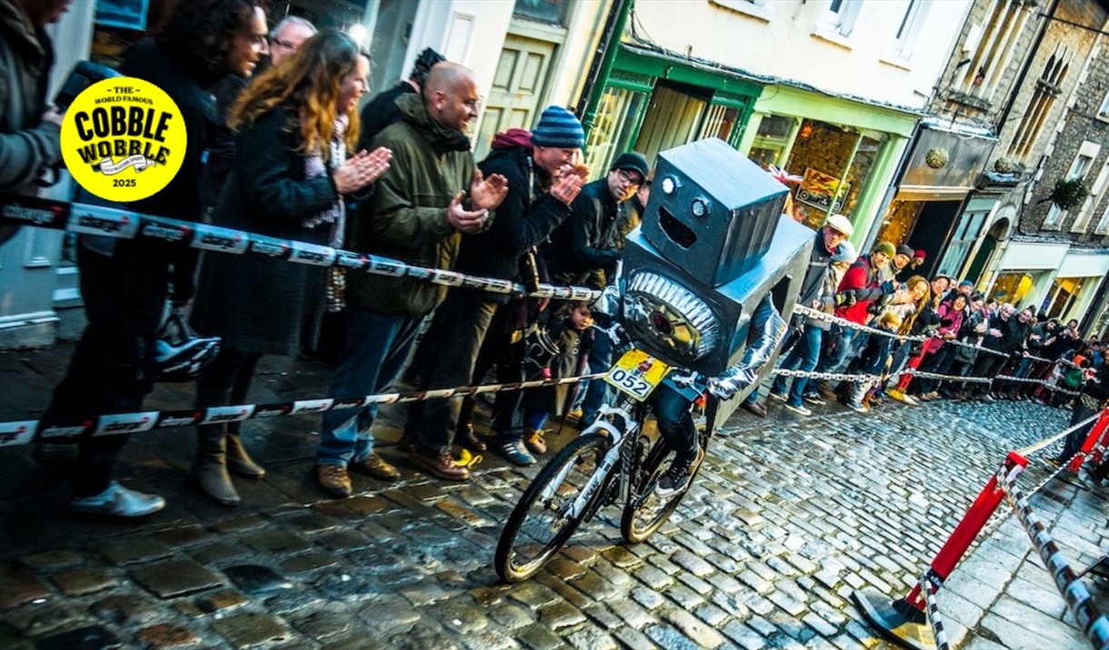 A person dressed as a robot riding up Catherine Hill in Frome  in the Cobble Wobble