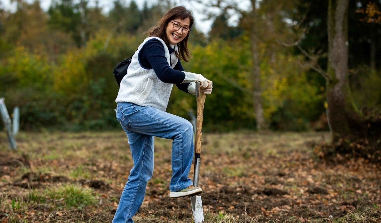 woman digging with spade in open woodland field