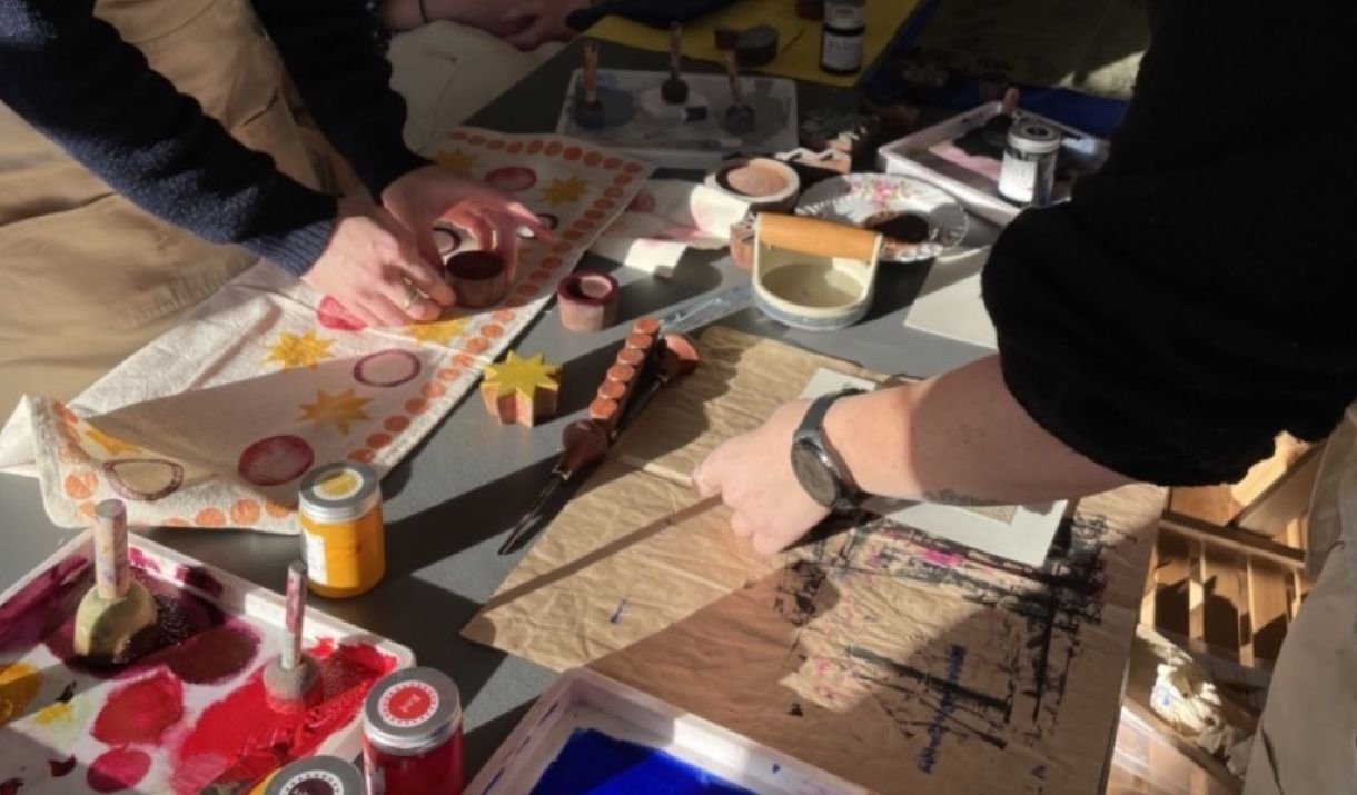 two women stand on opposite sides of a craft table, block printing and lino printing at the Love Makers Craft Cafe in Bath