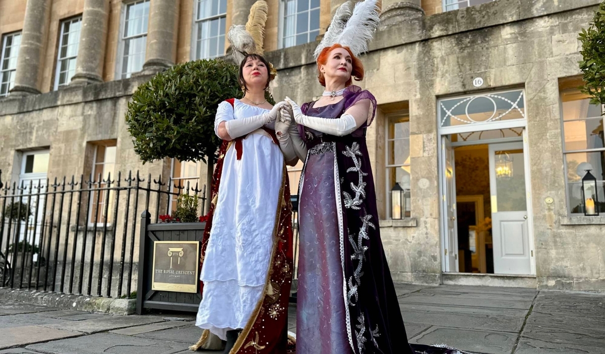 2 women dressed in Regency wear stood outside the Royal Crescent Hotel