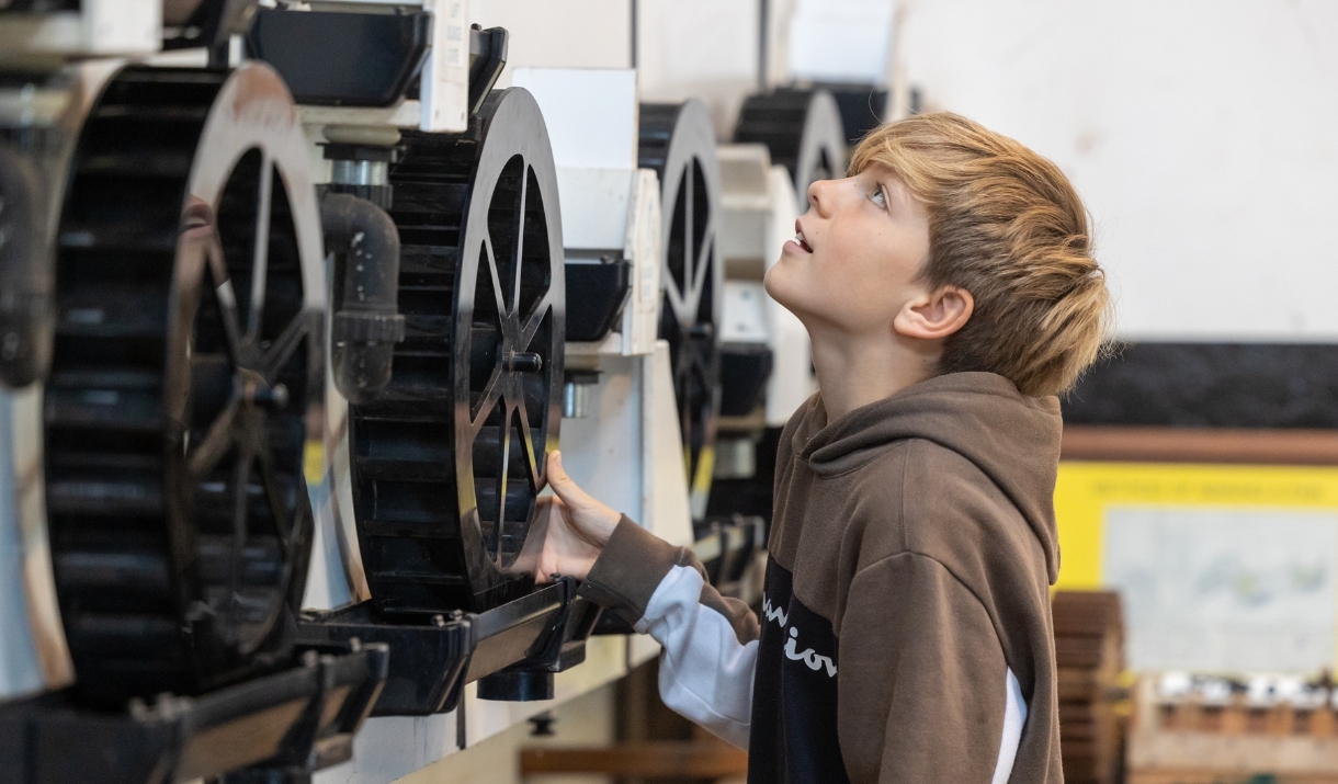 Boy looking at some large cogs on a machine at Saltford Brass Mill