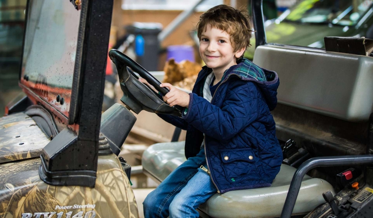 boy sitting on large outdoor mower