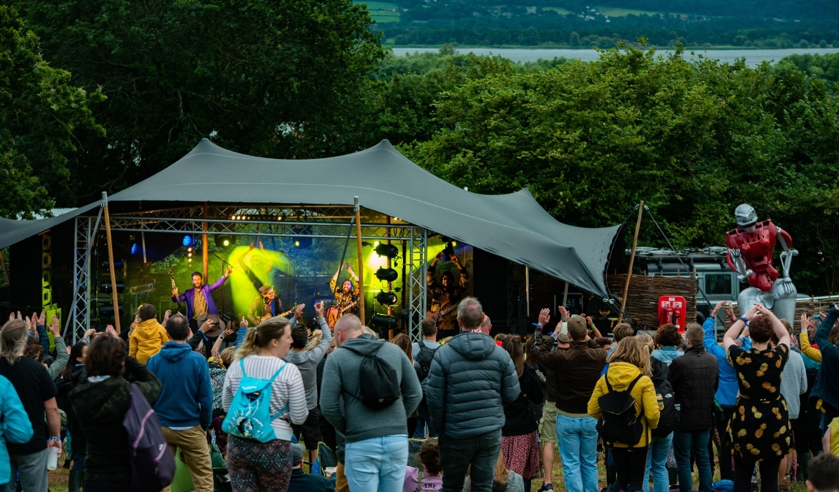 People stood in a field with a stage in the backgroun
