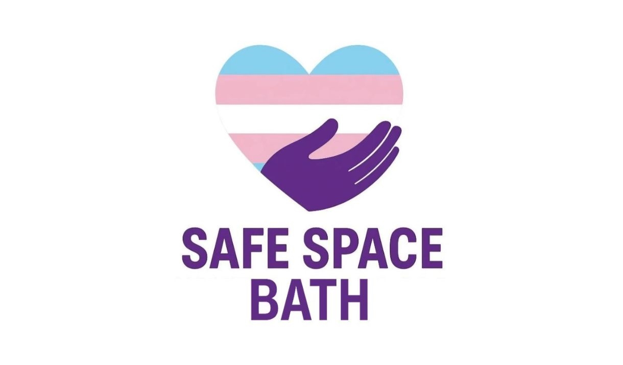 A simple bold graphic of a purple hand holding a heart with the trans flag on. Underneath in bold purple font it reads 'SAFE SPACE BATH'