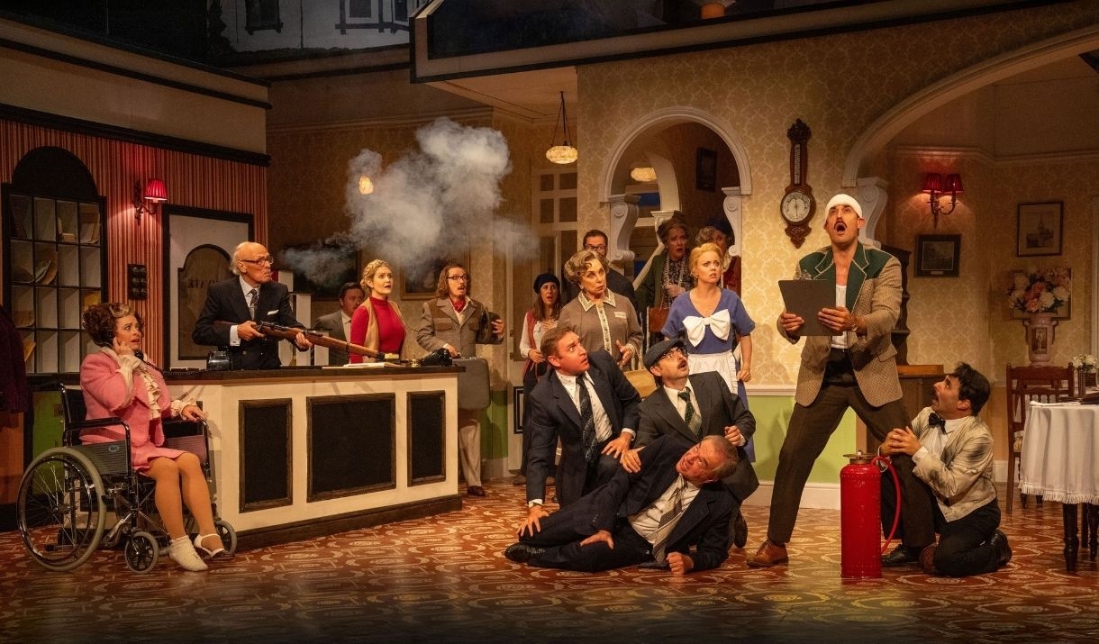 A scene from Fawlty Towers the play, containing most of the cast during a comedic moment.