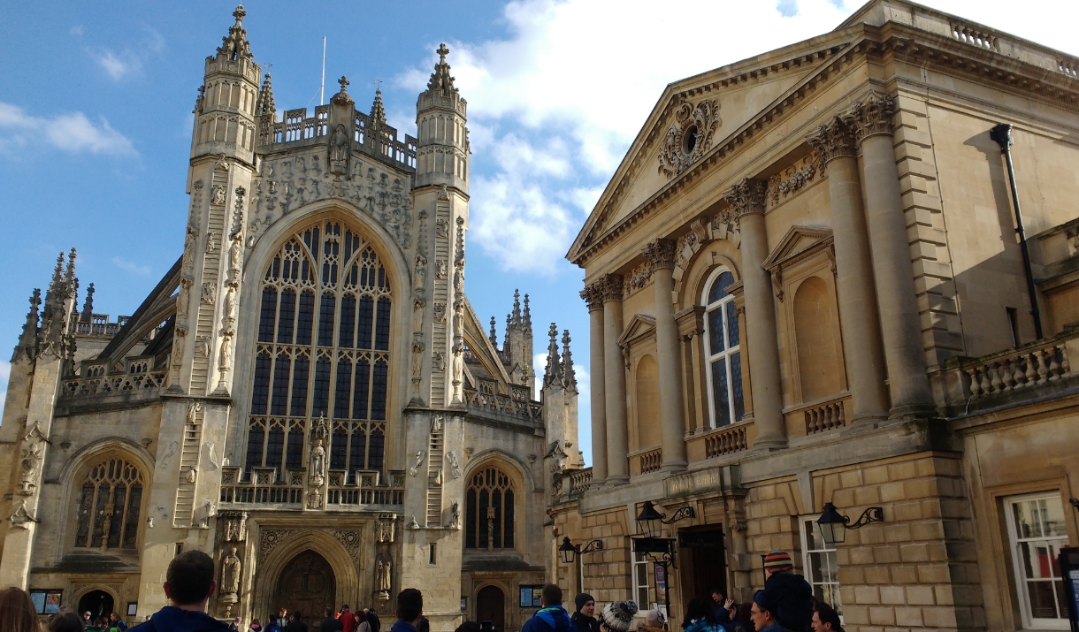 The front exterior of Bath Abbey on the left and The Roman Baths on the right.