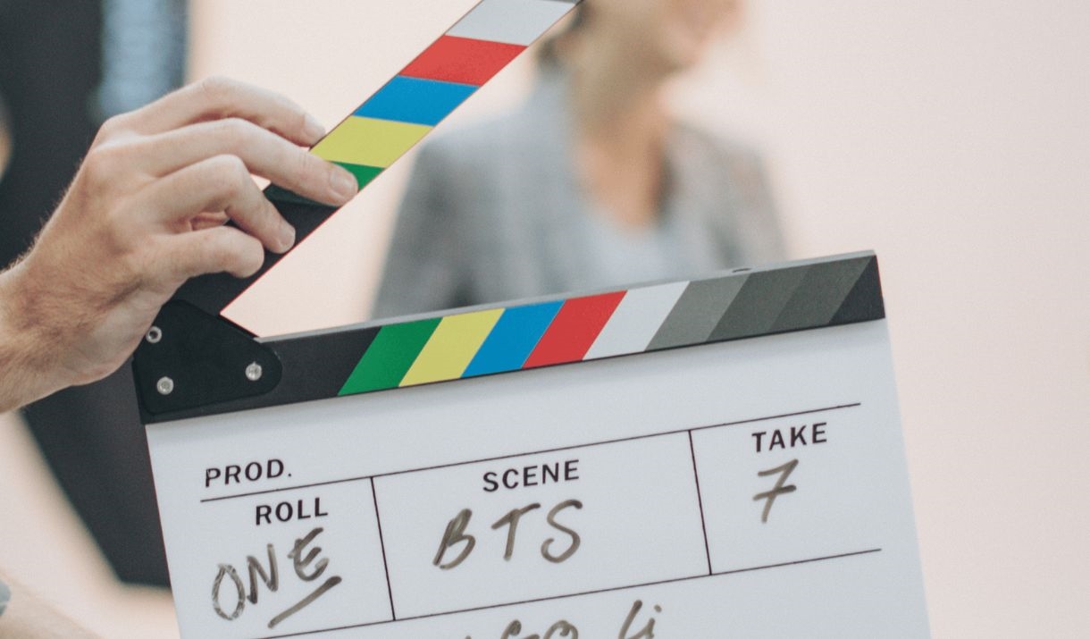 A clap board in front of an actor being filmed for cinema. Sparkfest logo on top corner