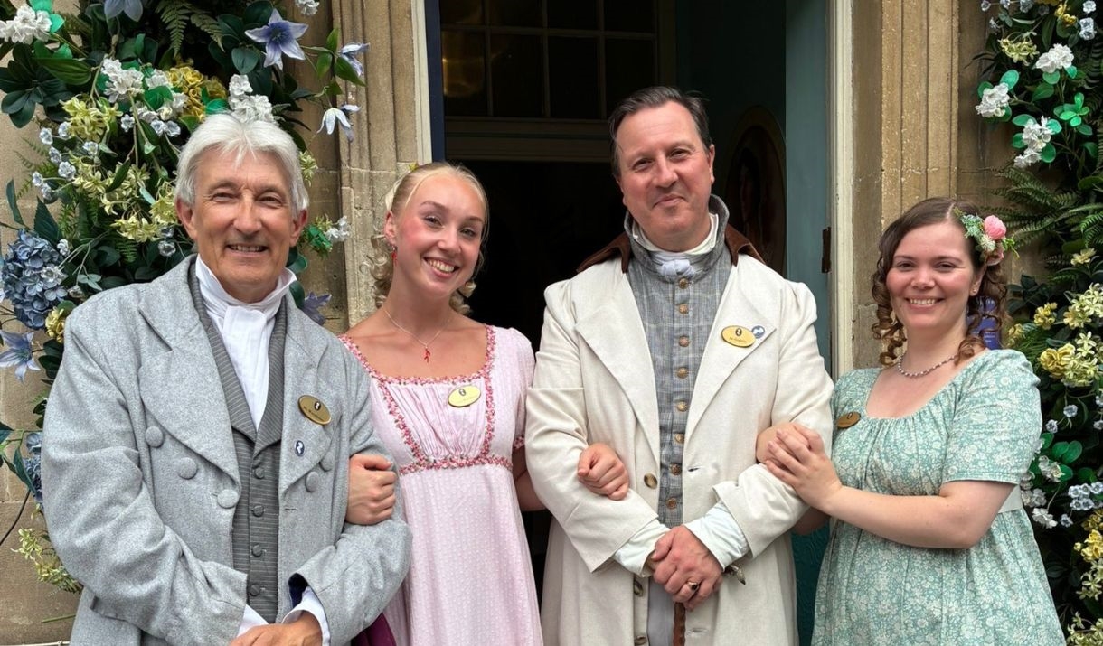 Four staff members dressed in regency clothing stand outside the entrance to the Jane Austen Centre.