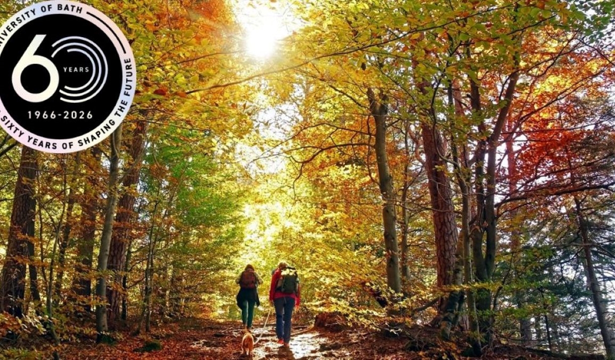 Man with his dog and a lady walking into a wooded area