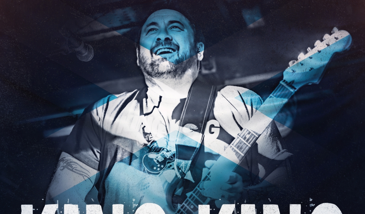 A blue-tinged image of a man playing a guitar