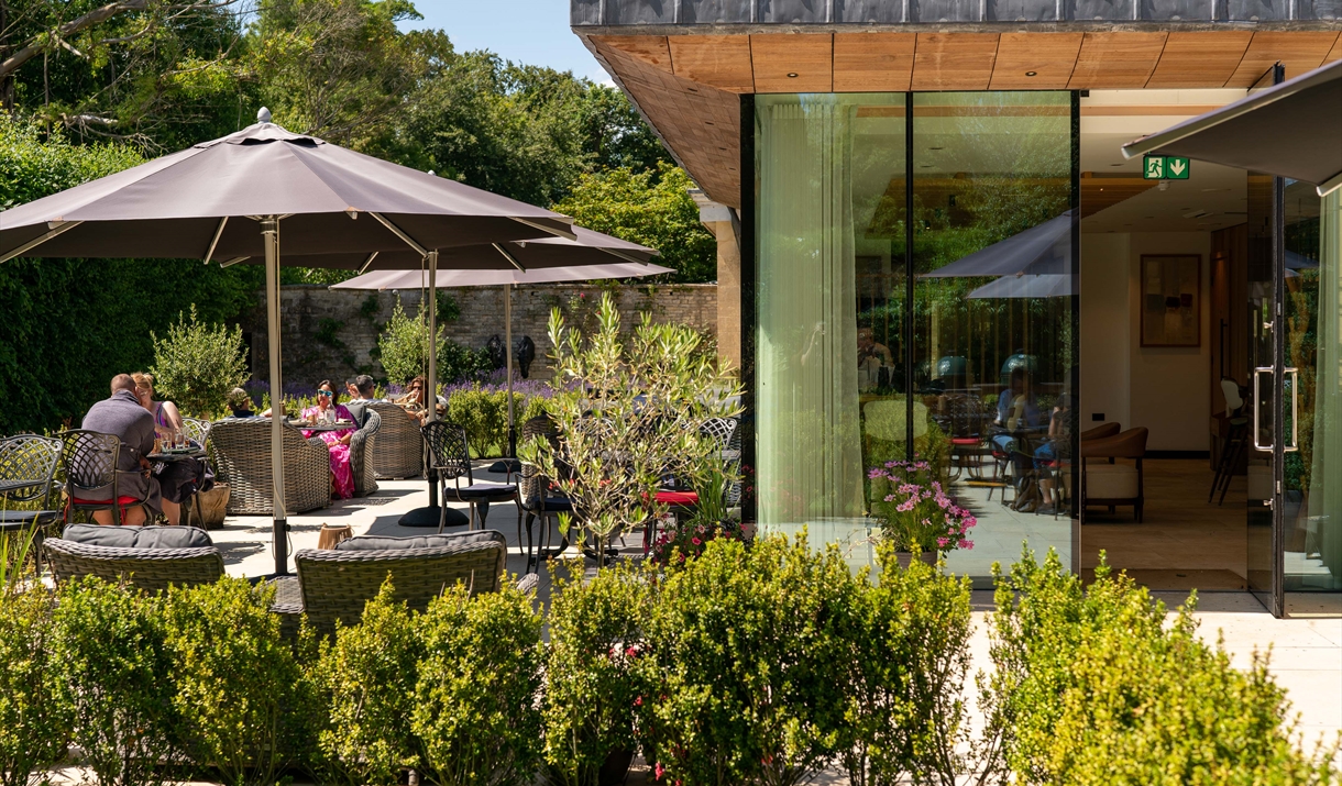 Outdoor restaurant patio with parasols and edge of the glass fronted restaurant.