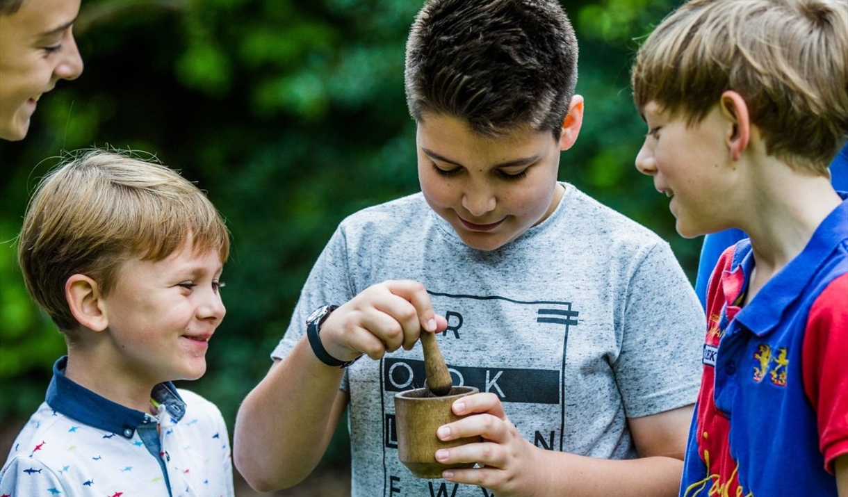child mixing materials in a pot with children looking on