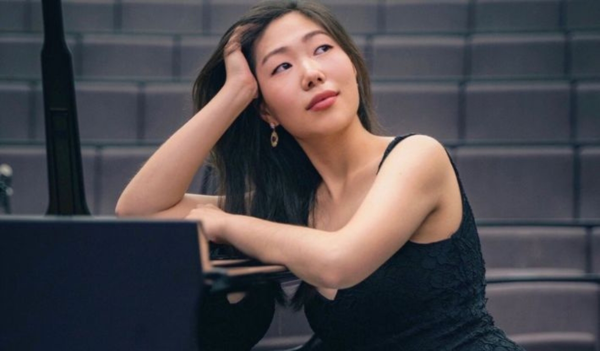 An image of Nurry Lee leaning on a piano.