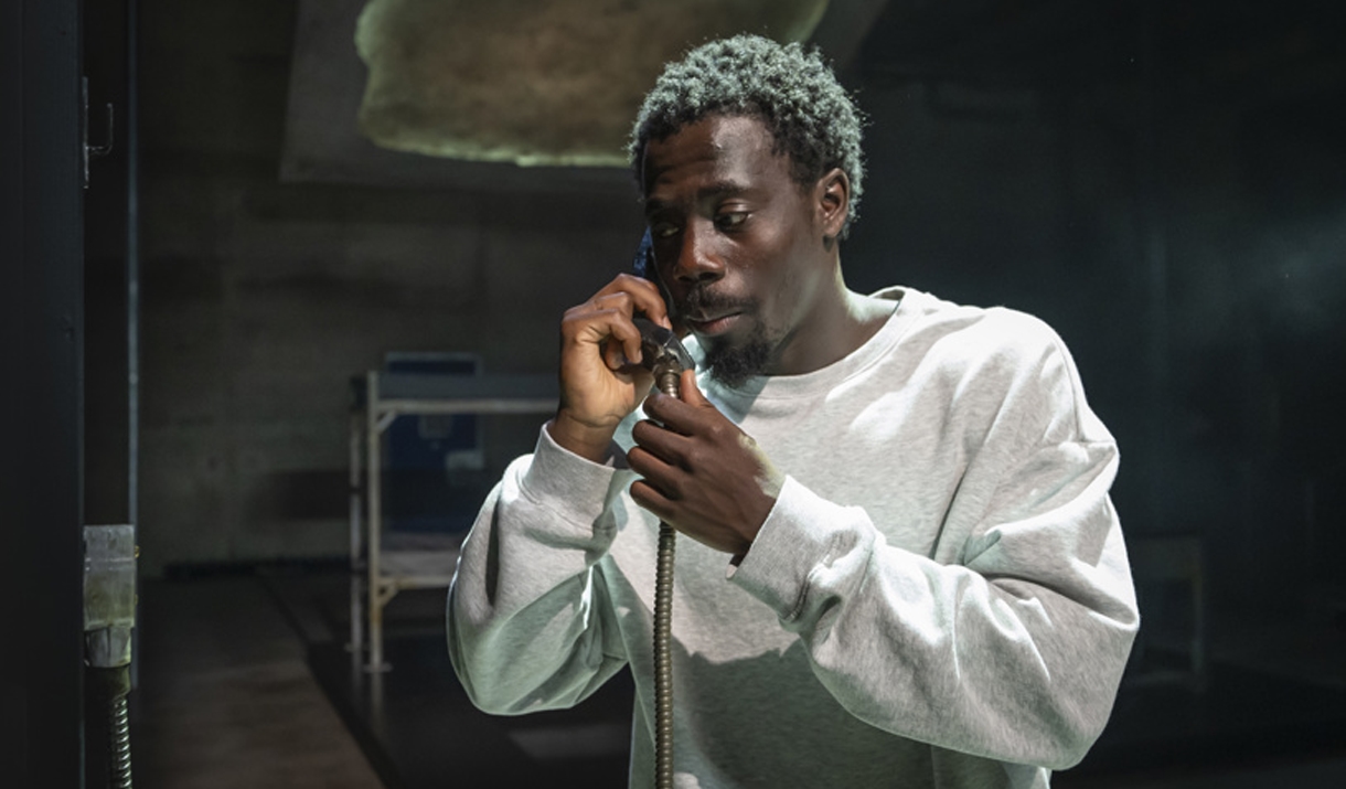 A man talks into wired telephone.