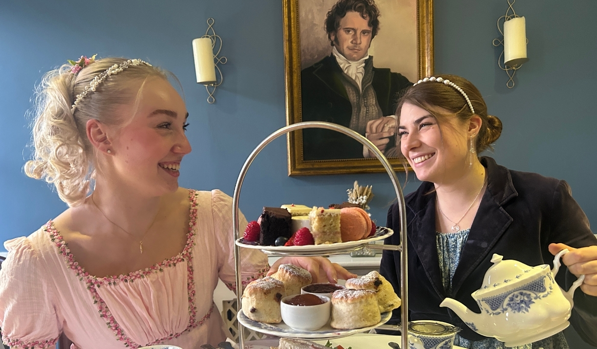 Two women having afternoon tea while dressed in period costume at the Regency Tea Room inside The Jane Austen Centre in Bath.