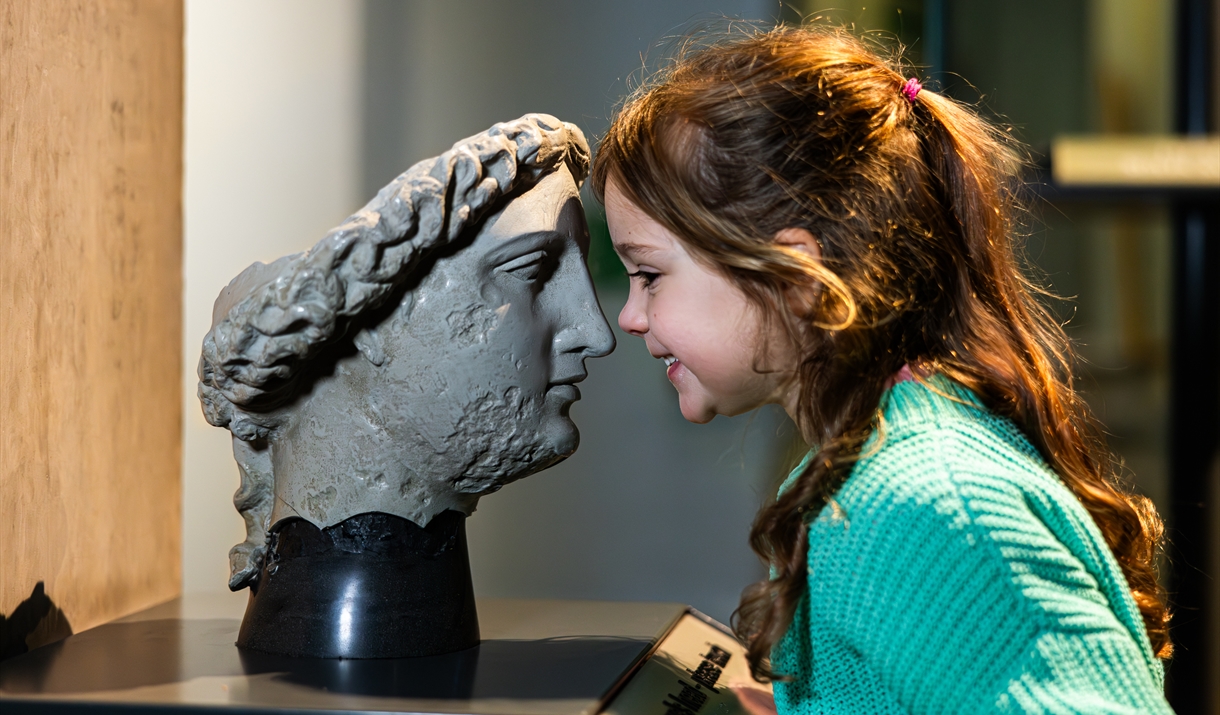 a young girl face to face with a model of a head