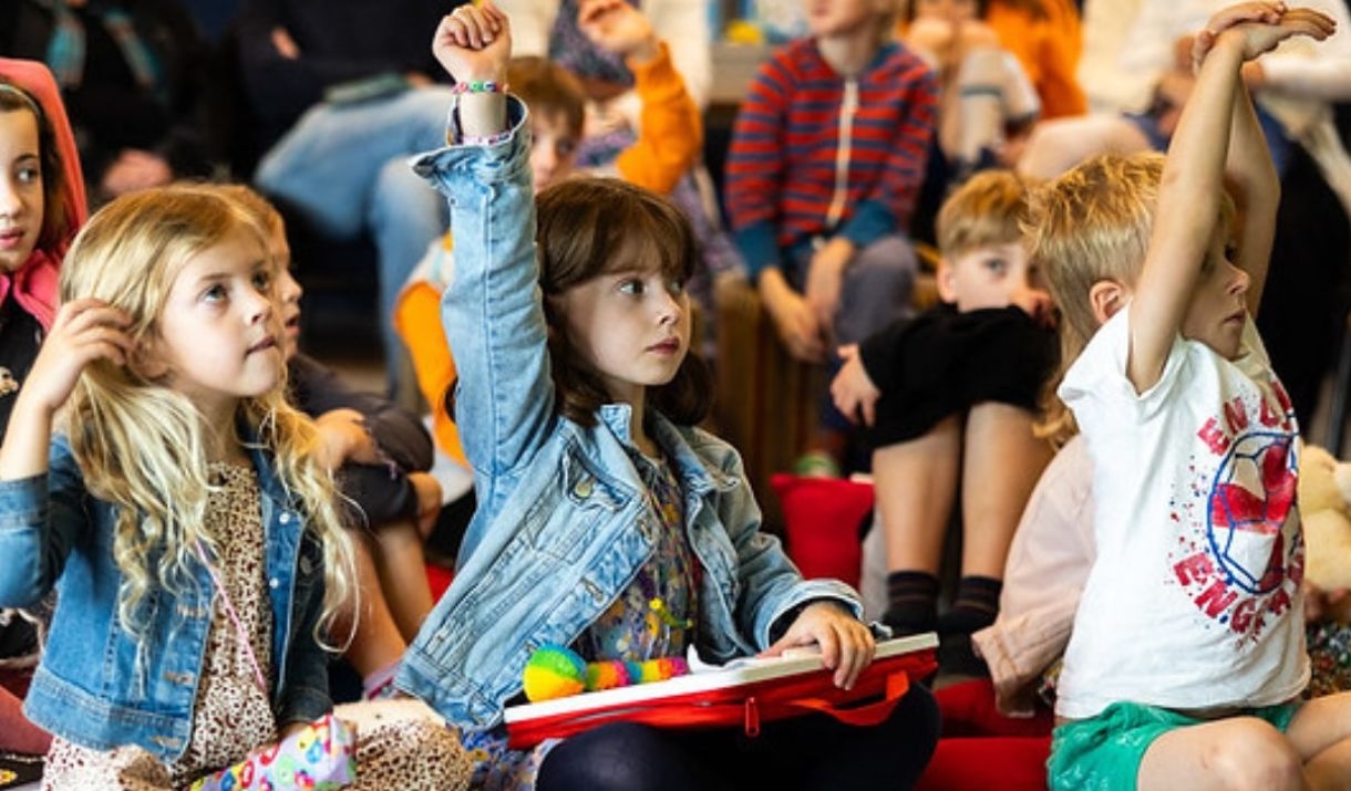 Children raising their hands at literature event