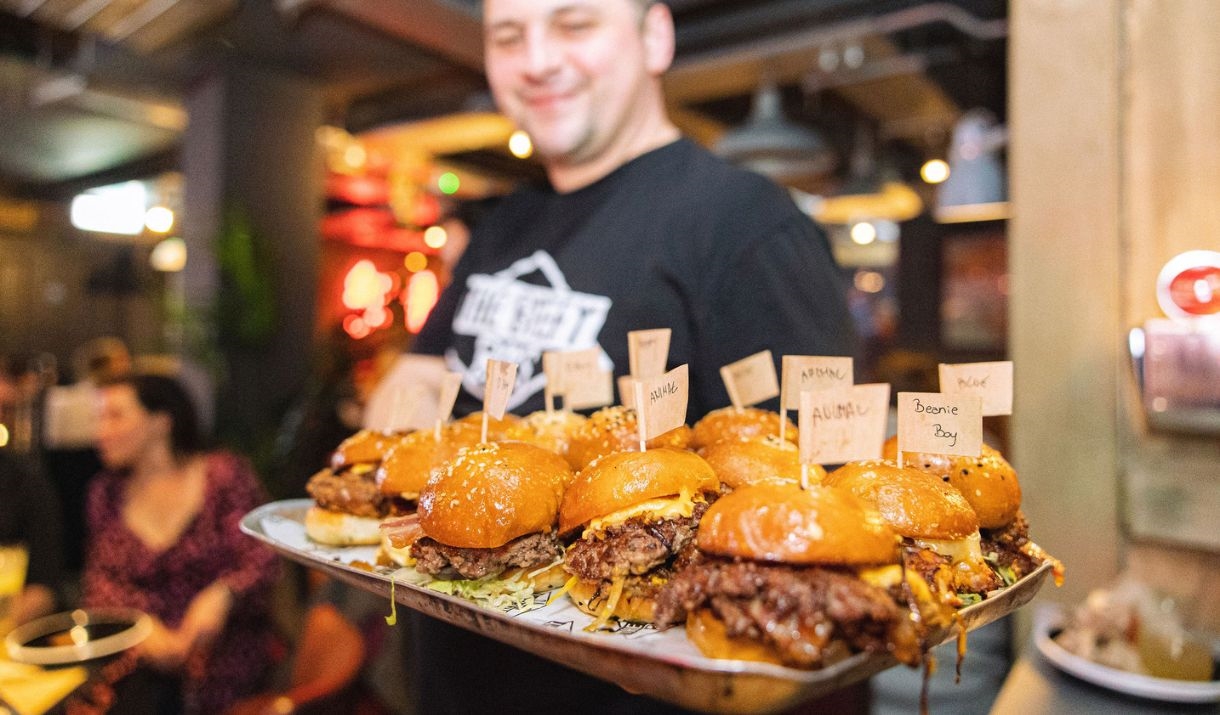 Person holding a tray of burgers