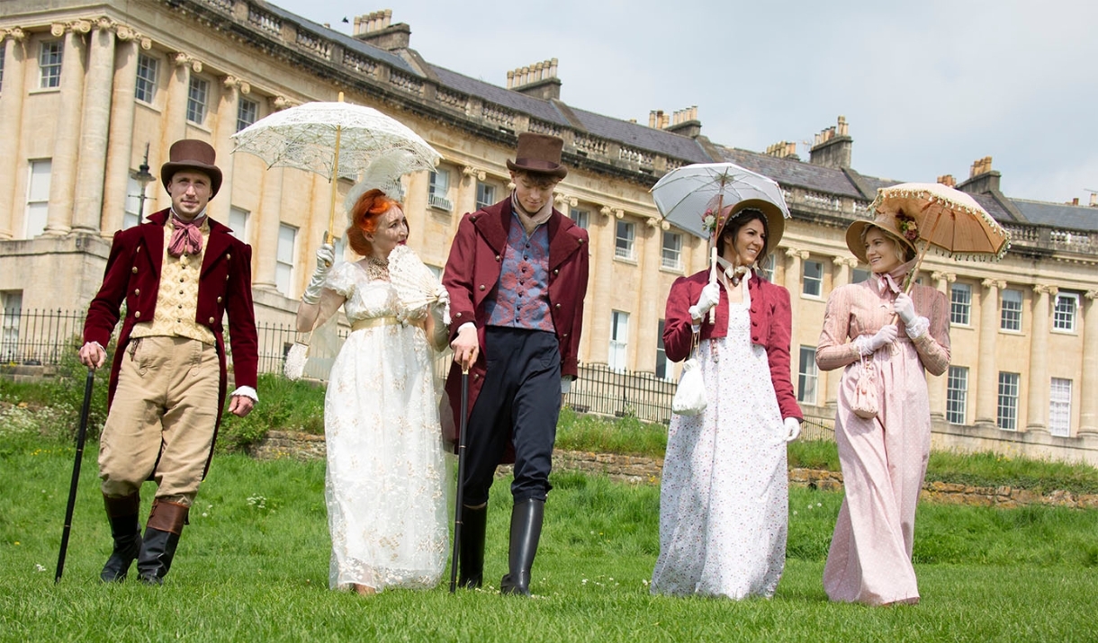 Five people walking in front of Bath's Royal Crescent wearing period dress