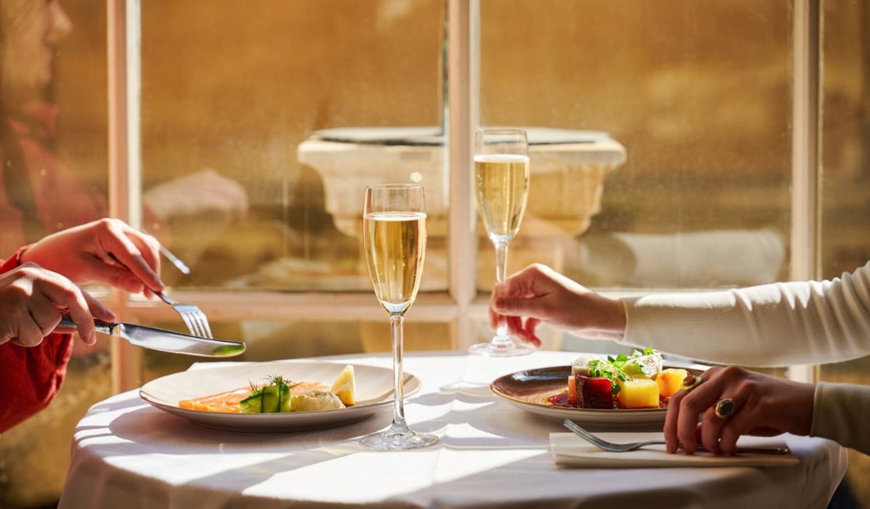 An image of two friends enjoying a delicious evening meal in the sunlit Pump Room