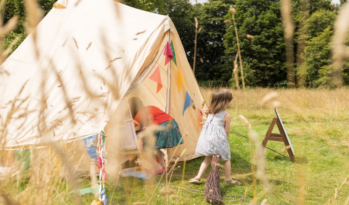 Children playing in the dress up tent in Lacock Abbey's parkland.