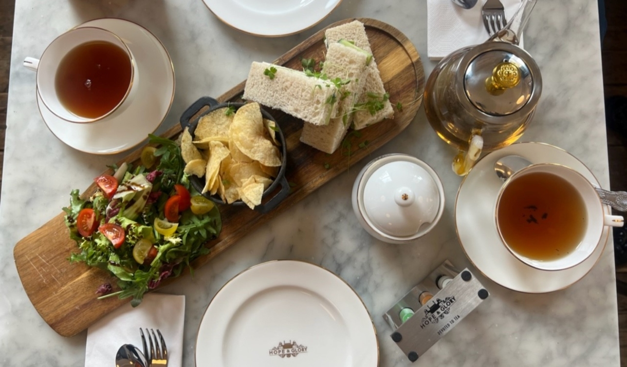 A sandwich, crisps and salad surrounded by tea and white crockery at The Abbey Tea Bar, Bath